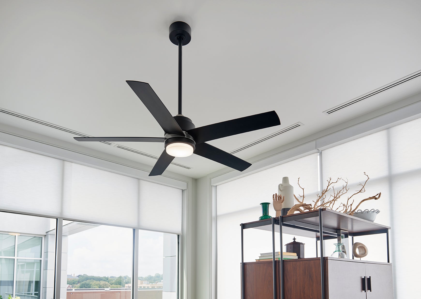 Black ceiling fan in a room with large windows and a modern interior.