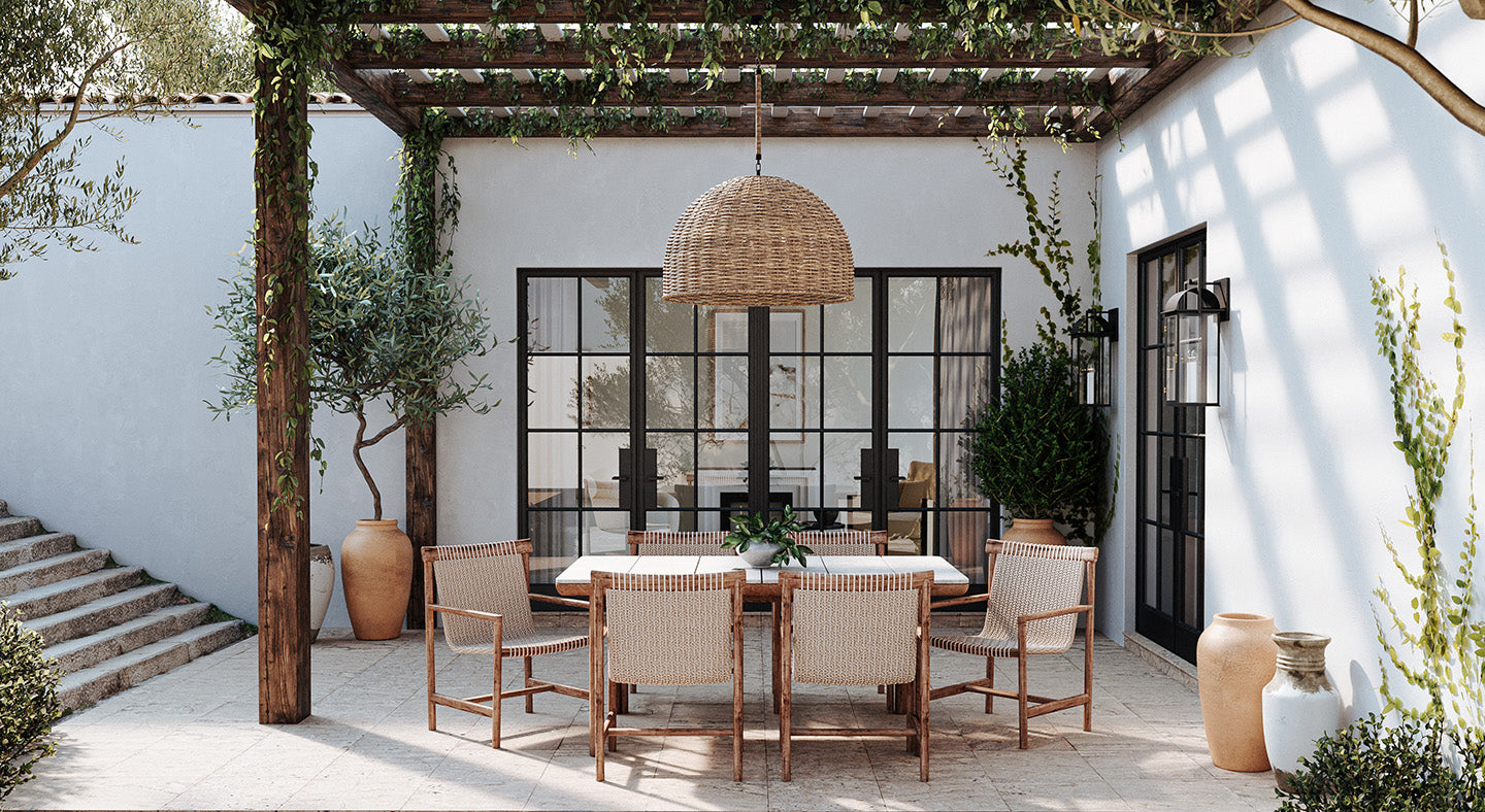 Large outdoor patio area with a dining table and chairs, large wicker chandelier, and two black wall lanterns under a vine-covered pergola.