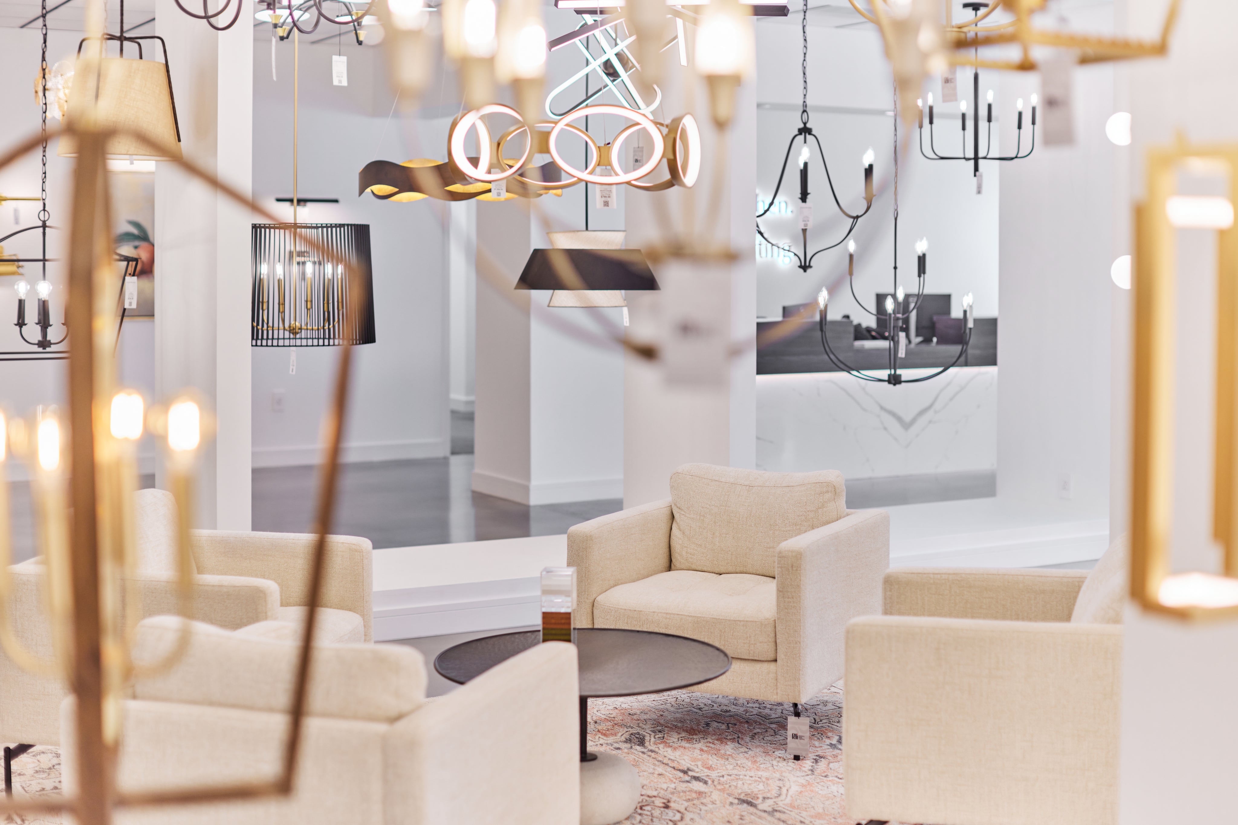 Modern interior design with beige armchairs, a coffee table, and decorative lights.