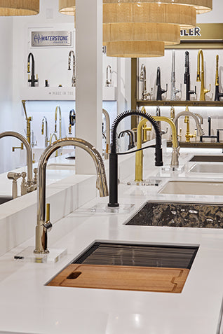 Modern kitchen sink with various faucet options in a showroom setting.