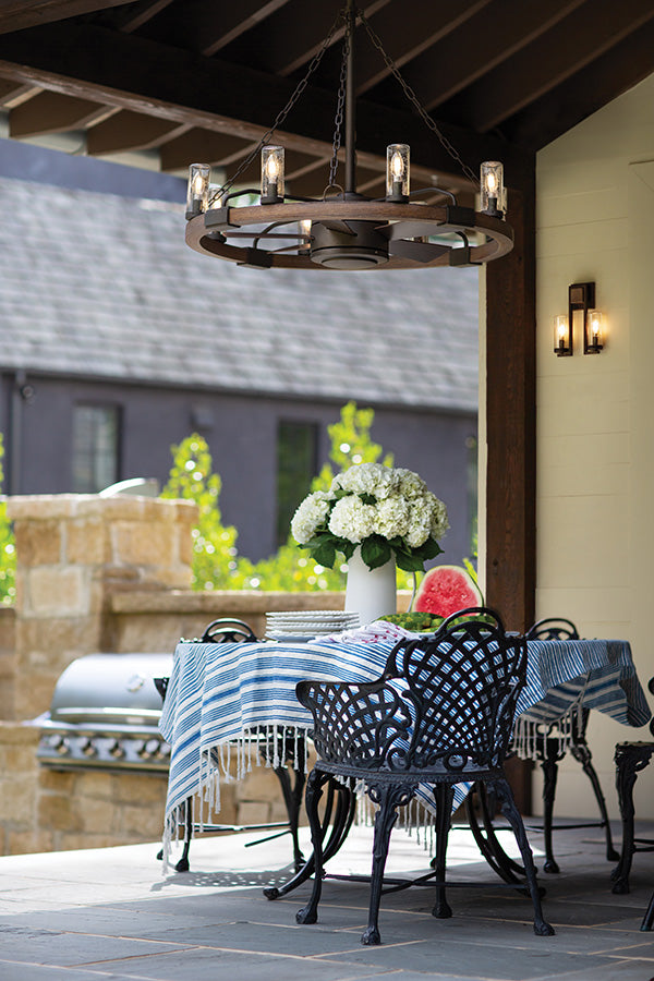 Outdoor patio with table, chairs, and a blue tablecloth on a patio with a wooden outdoor chandelier overhead.