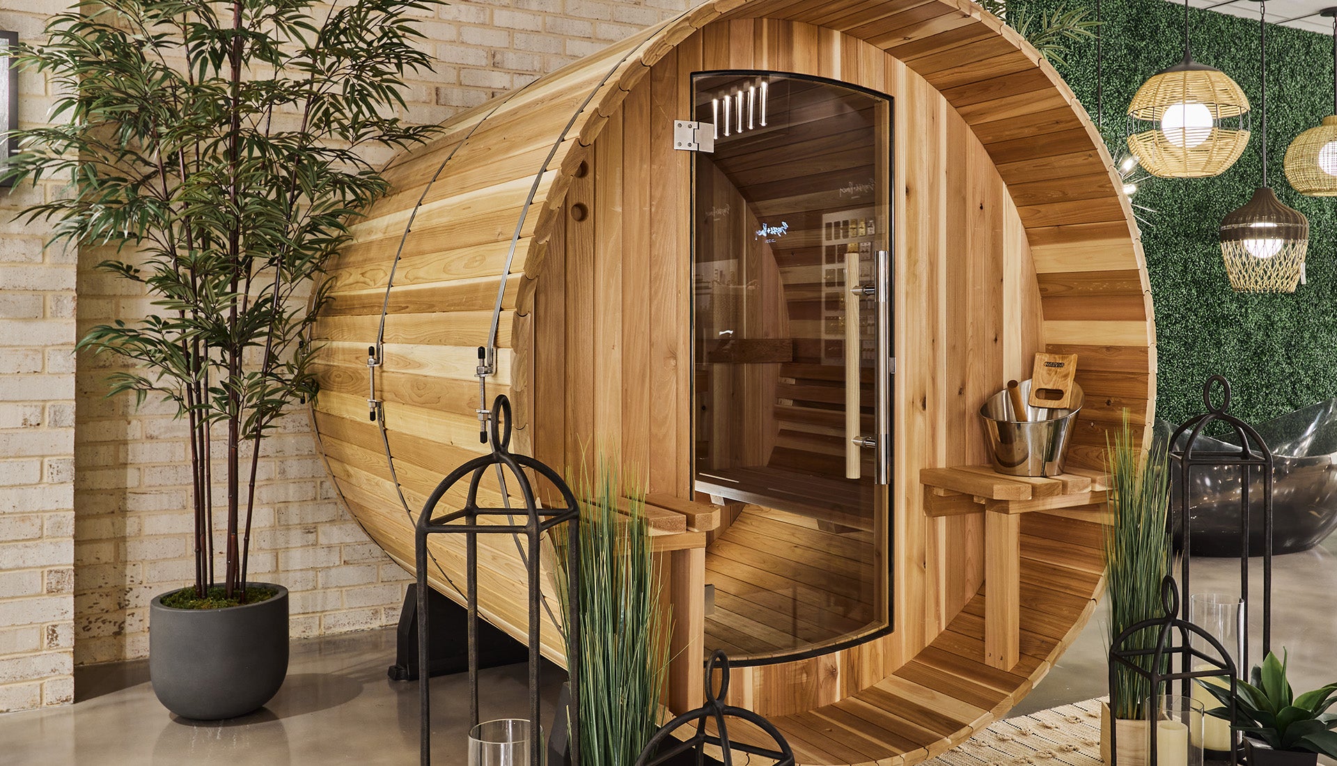 Wooden barrel-shaped sauna with plants and decor in a showroom.