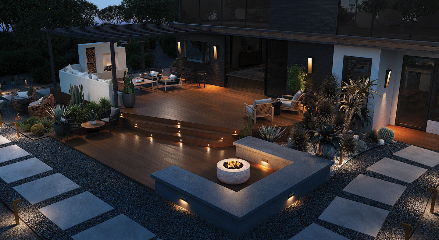 Evening view of a well-lit modern outdoor patio with fire pit and seating area.