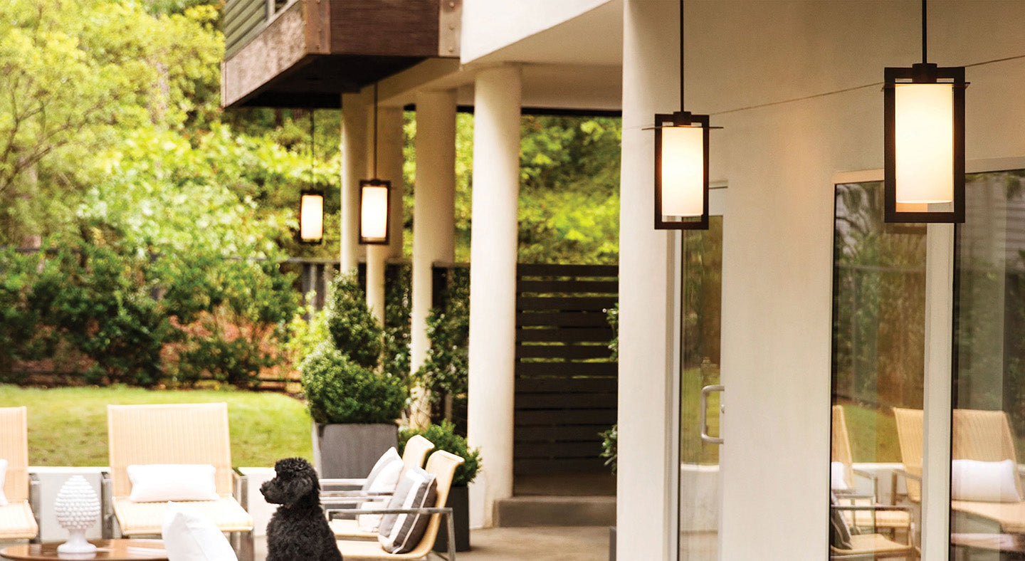 High-end outdoor patio with four pendant lights, lawn chairs, and a black dog sitting. 