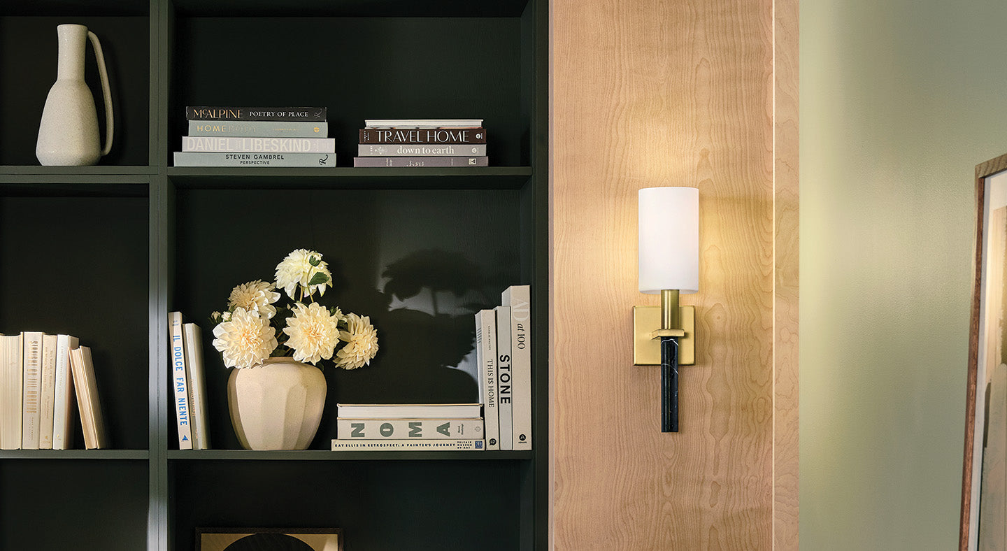 Decorative wall sconce on a wooden panel with a bookshelf and books in the background.