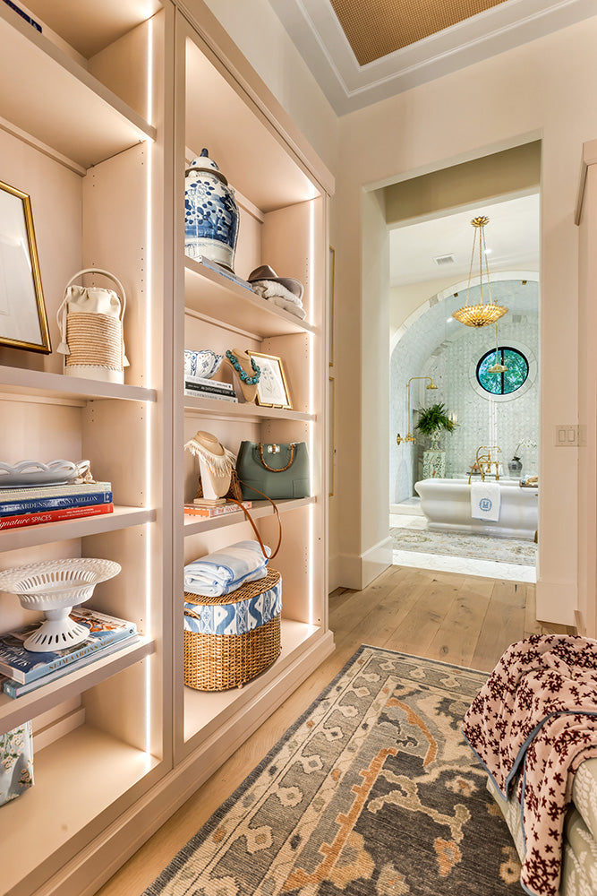 Custom bookshelf with integrated edge lighting and decorative items, with a bathroom in the background.