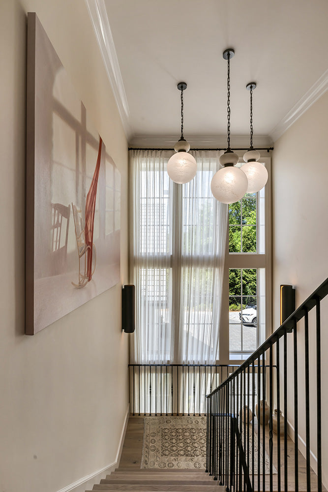 Staircase with three modern pendant lights and a large window in a home interior.