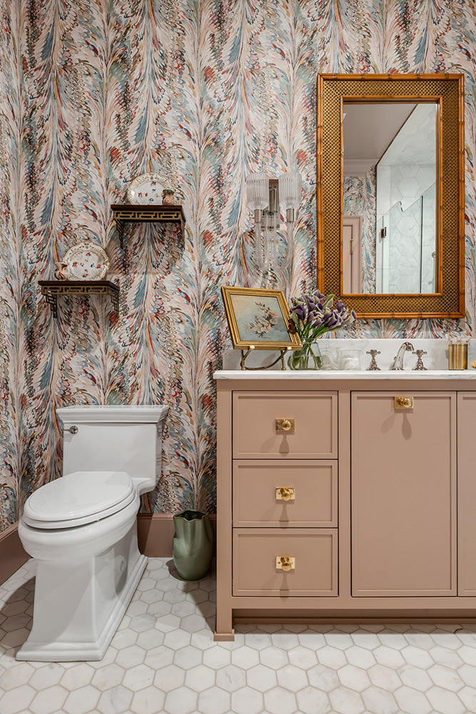 Guest bathroom with patterned wallpaper, painted vanity with gold Ashley Norton hardware, and decorative elements.