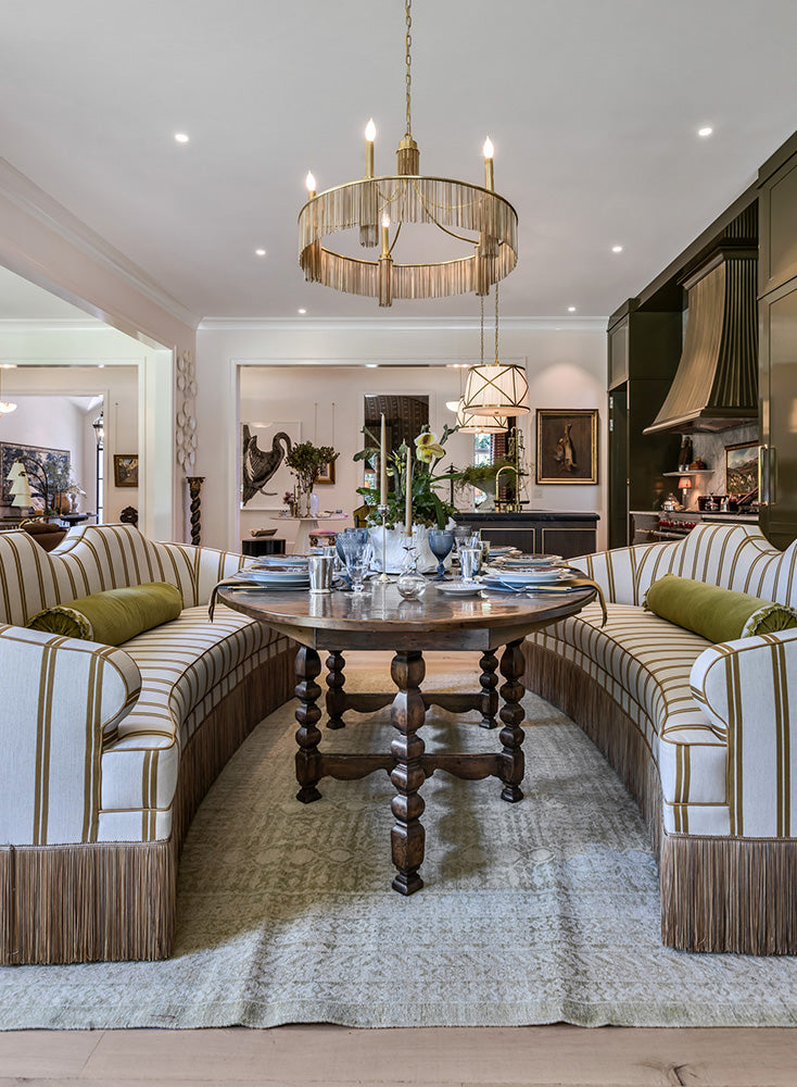 Luxurious dining area with an antique wooden table, striped sofas and a gorgeous gold chandelier